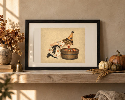 Vintage Halloween apple bobbing print in a black frame on an oak shelf with heirloom pumpkins