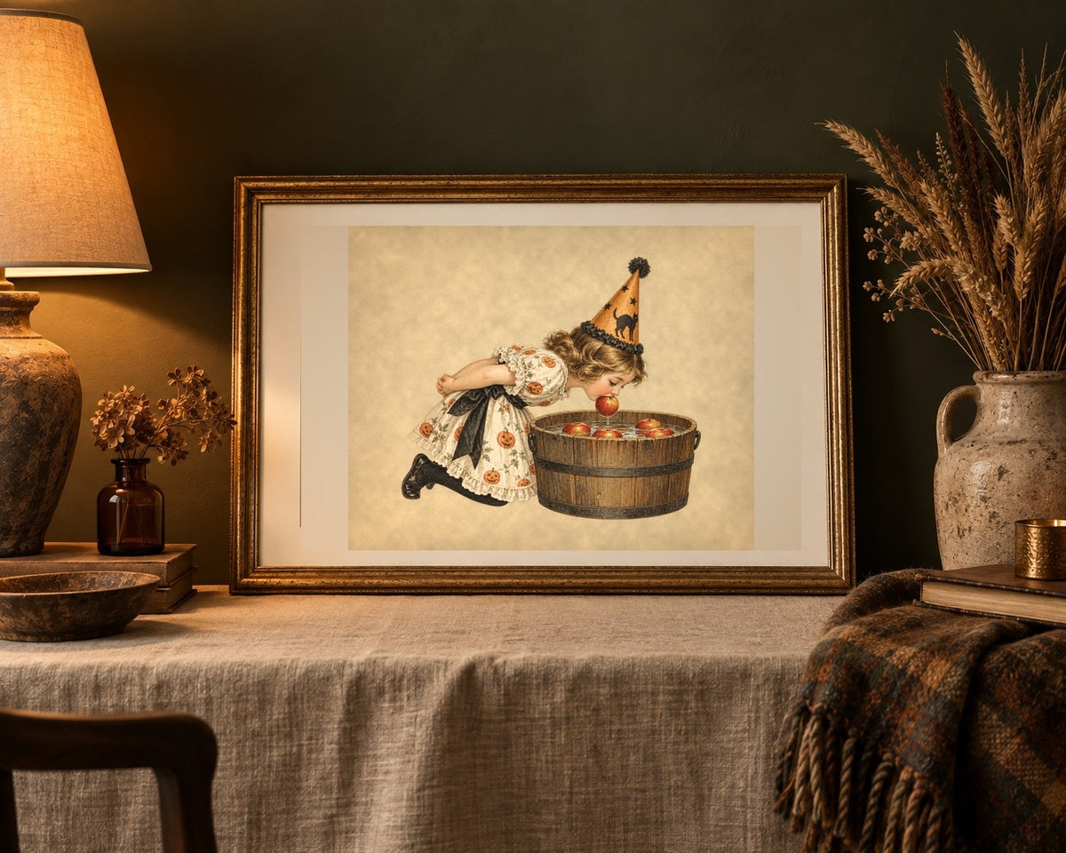 Vintage Halloween apple bobbing print in an antique gold frame on a linen table against an olive wall