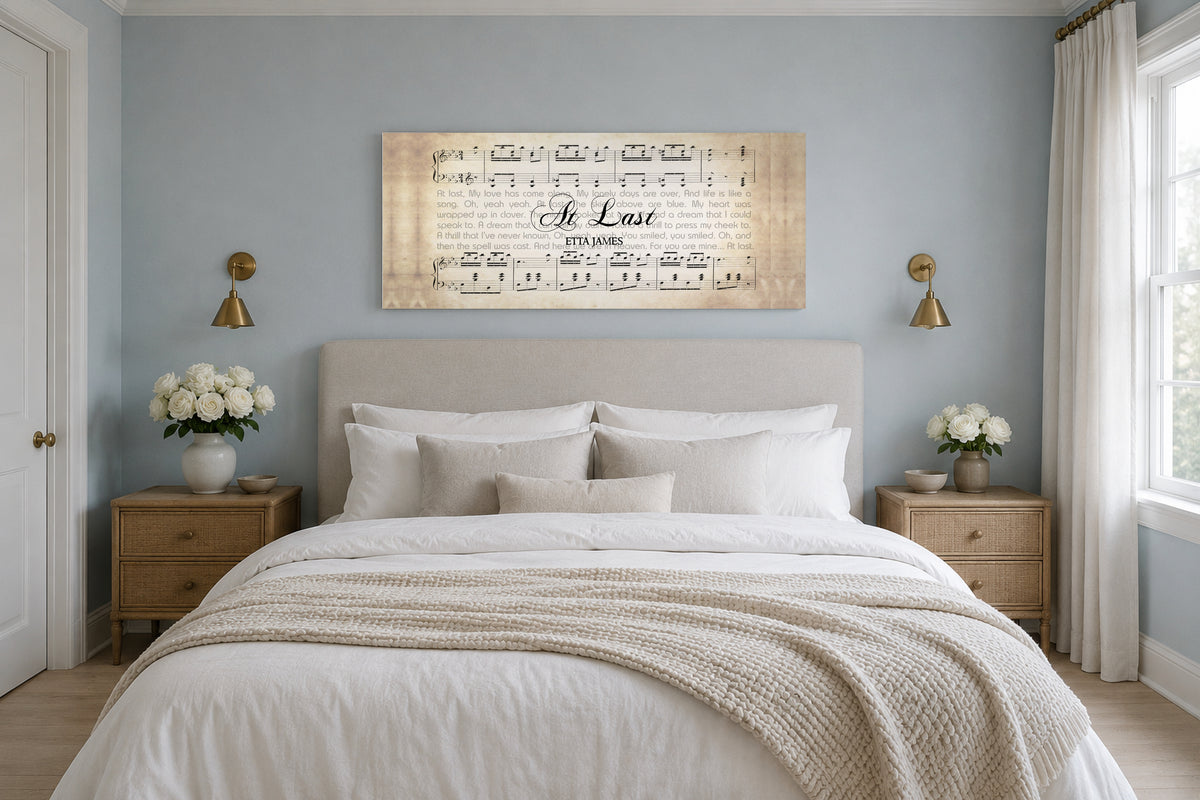 At Last sheet music lyric canvas above an oatmeal linen headboard in a dusty blue bedroom with brass sconces and white roses