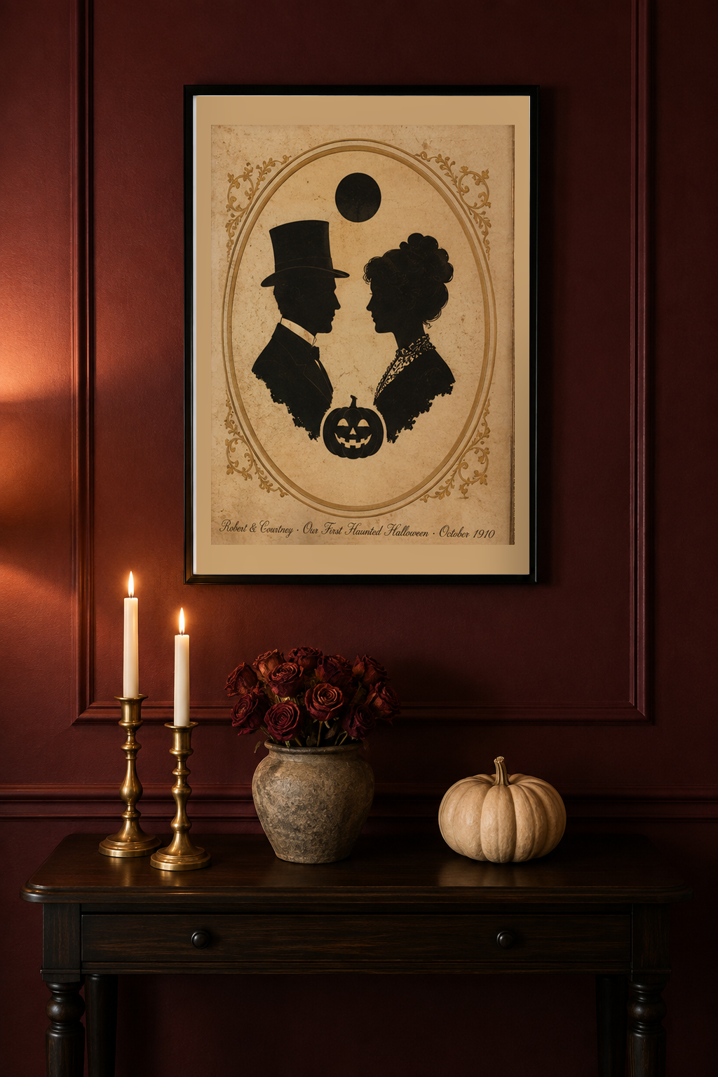 Personalized couple first haunted Halloween 8x10 print framed on an oxblood panelled wall above a black walnut console with brass taper candles, dried roses and a pale pumpkin