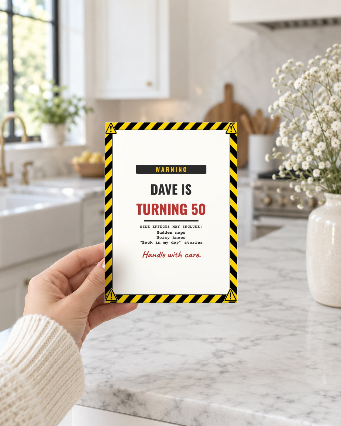 Hand holding the warning label birthday card in a bright kitchen