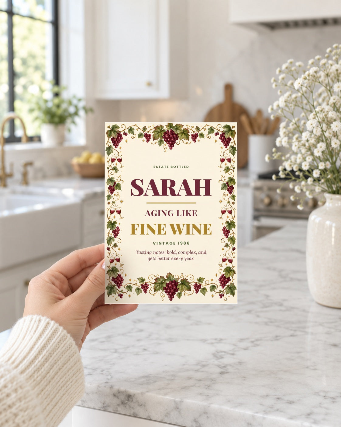 Hand holding the wine label birthday card in a bright kitchen