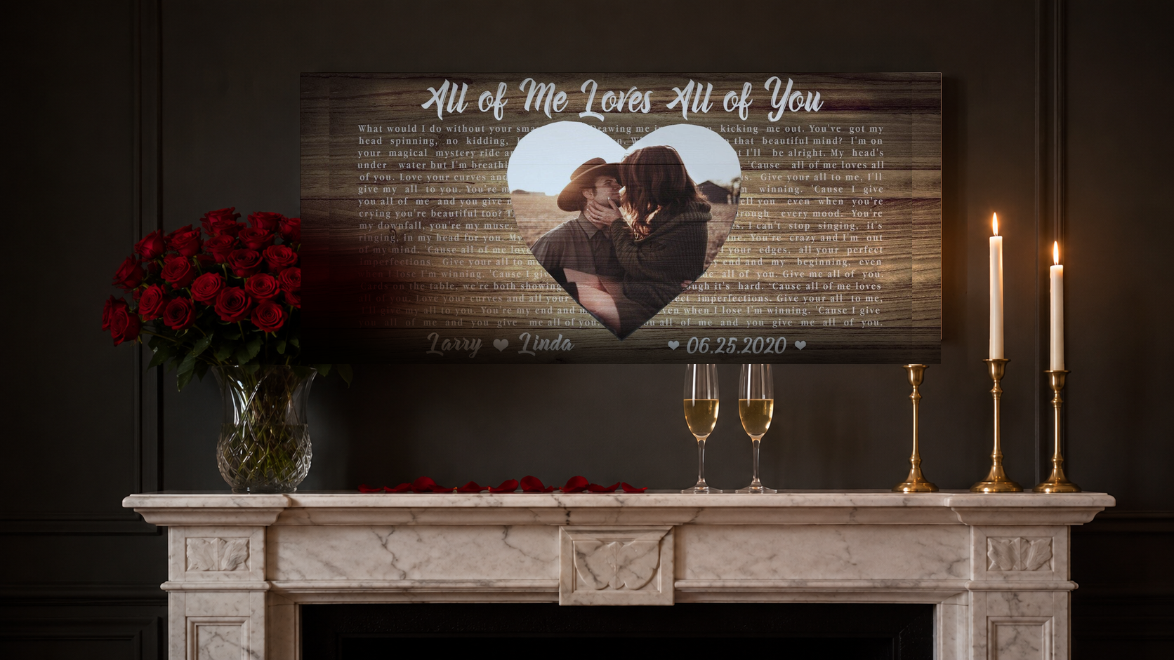 Personalized wedding song lyrics canvas above a marble anniversary mantel with red roses, champagne and brass candles