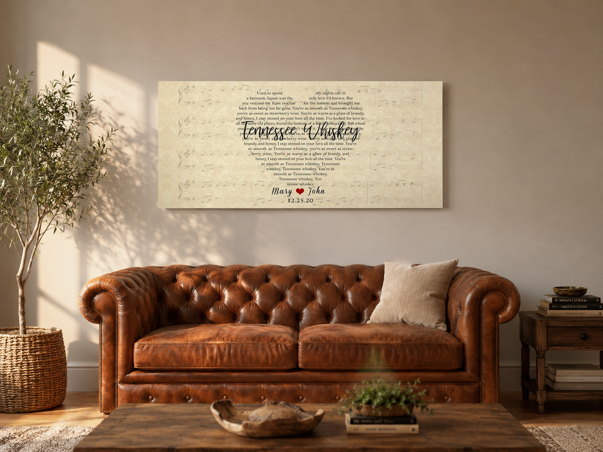 Heart shaped song lyric canvas with couple names and date hanging above a cognac leather sofa in a sunlit living room