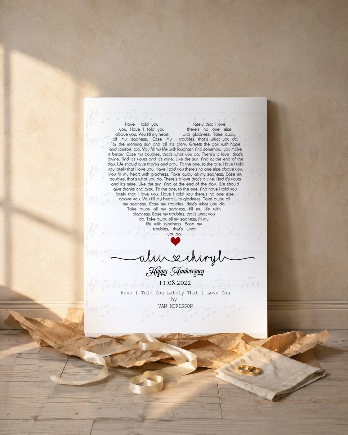 Personalized song lyrics canvas unwrapped as an anniversary gift with kraft paper, satin ribbon and gold wedding rings