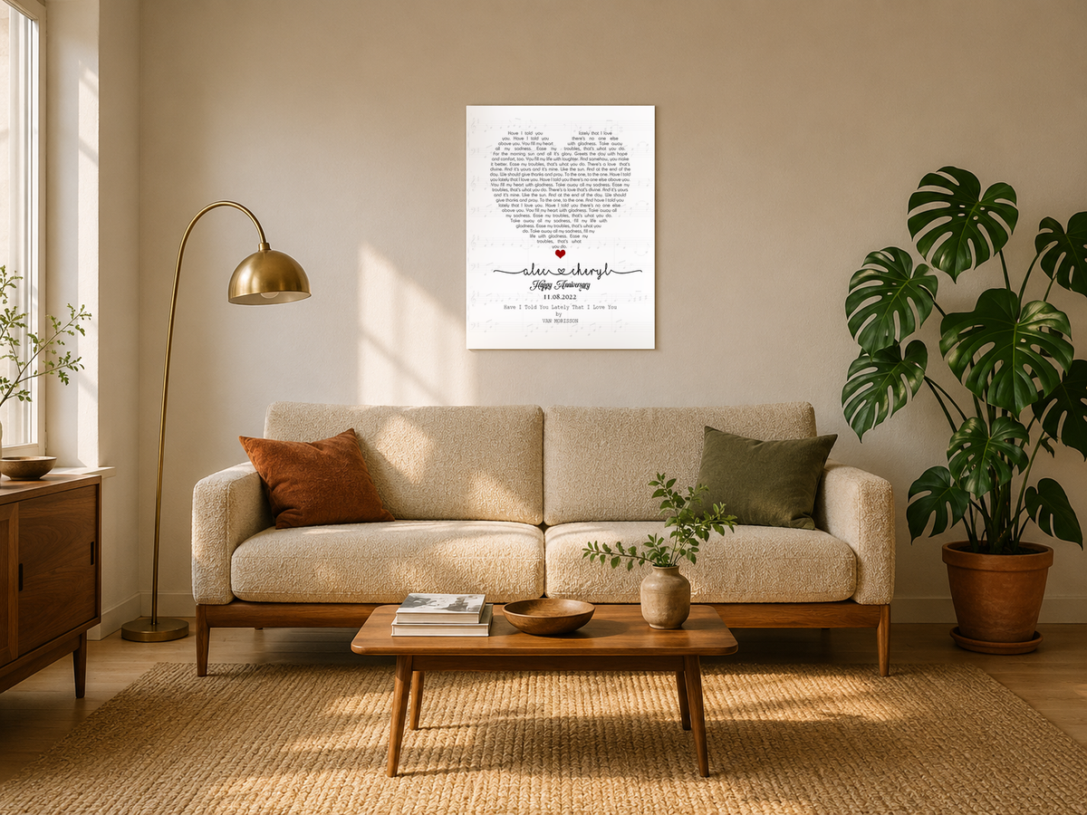 Personalized anniversary song lyrics canvas with couple names and date hanging above a boucle sofa in a sunlit mid-century living room