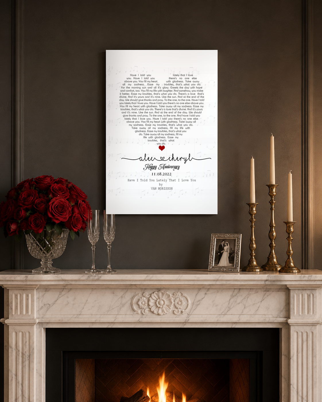 Romantic anniversary song lyrics canvas above a marble mantel with red roses, champagne flutes and brass candles