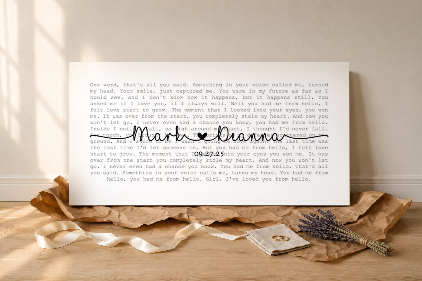 Personalized wedding song lyric canvas unwrapped as a gift with kraft paper, ribbon and gold rings