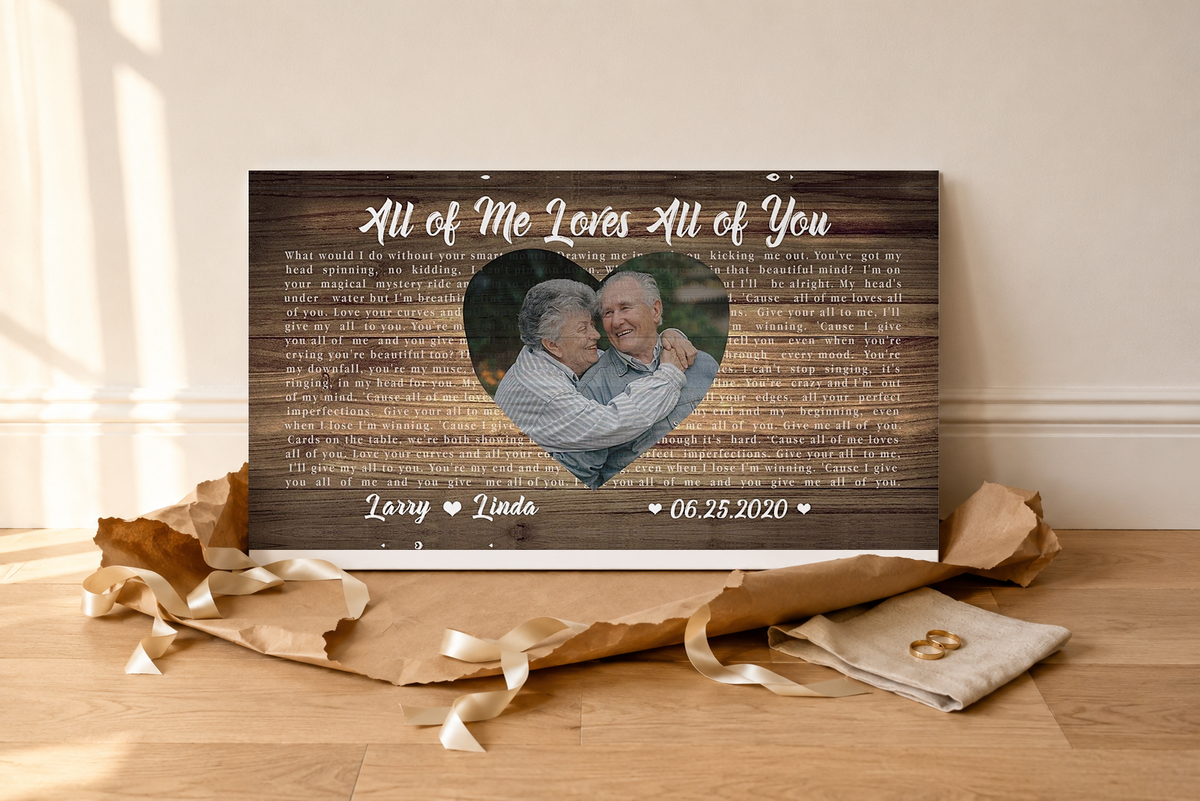 Personalized couple song lyric canvas unwrapped on an oak floor with kraft paper, ribbon and gold wedding rings