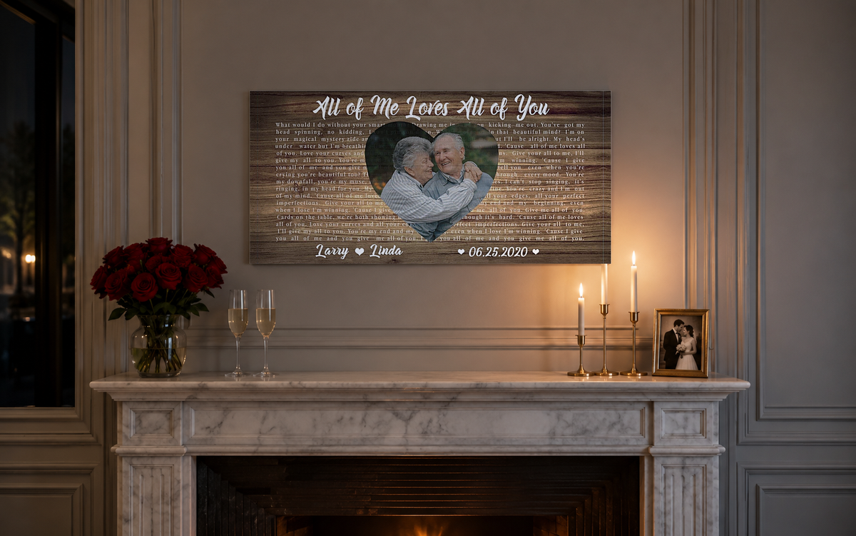 Custom anniversary song lyric canvas above a white marble mantel with red roses, champagne flutes and brass candles