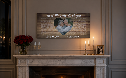 Custom anniversary song lyric canvas above a white marble mantel with red roses, champagne flutes and brass candles