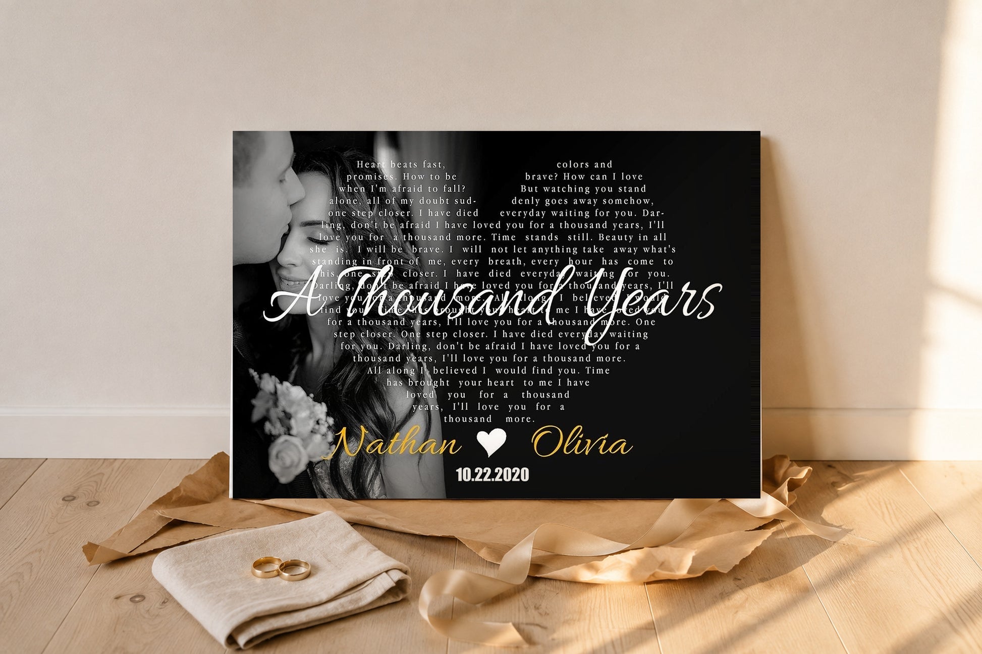 Personalized song lyrics canvas gift unwrapped on an oak floor with kraft paper, satin ribbon and gold wedding rings