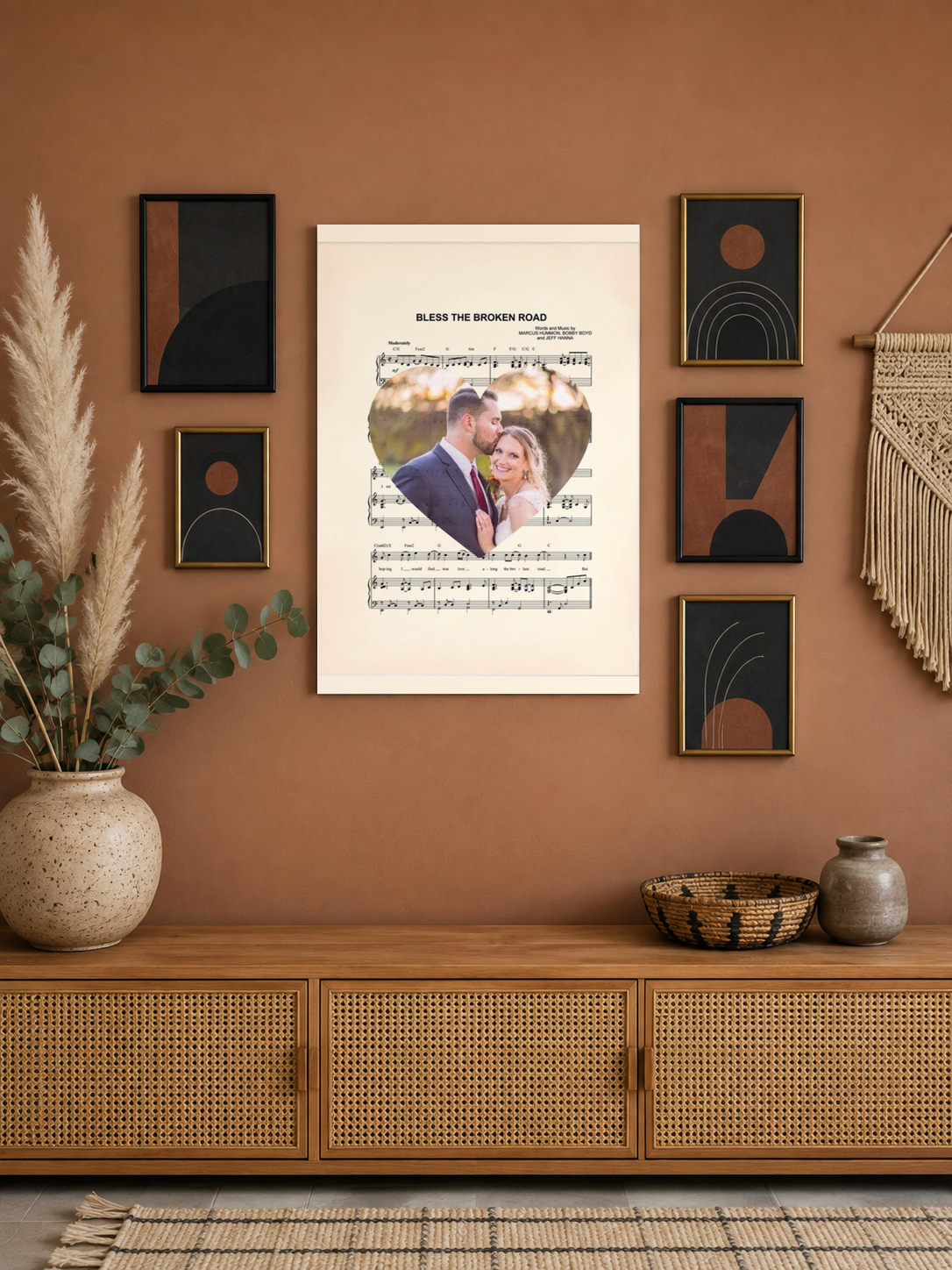 Custom wedding song lyrics print as the centrepiece of a modern boho gallery wall on a clay-toned wall with pampas grass and a rattan console