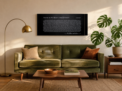 Personalized song lyric canvas hanging above a sage green mid-century sofa in a sunlit living room