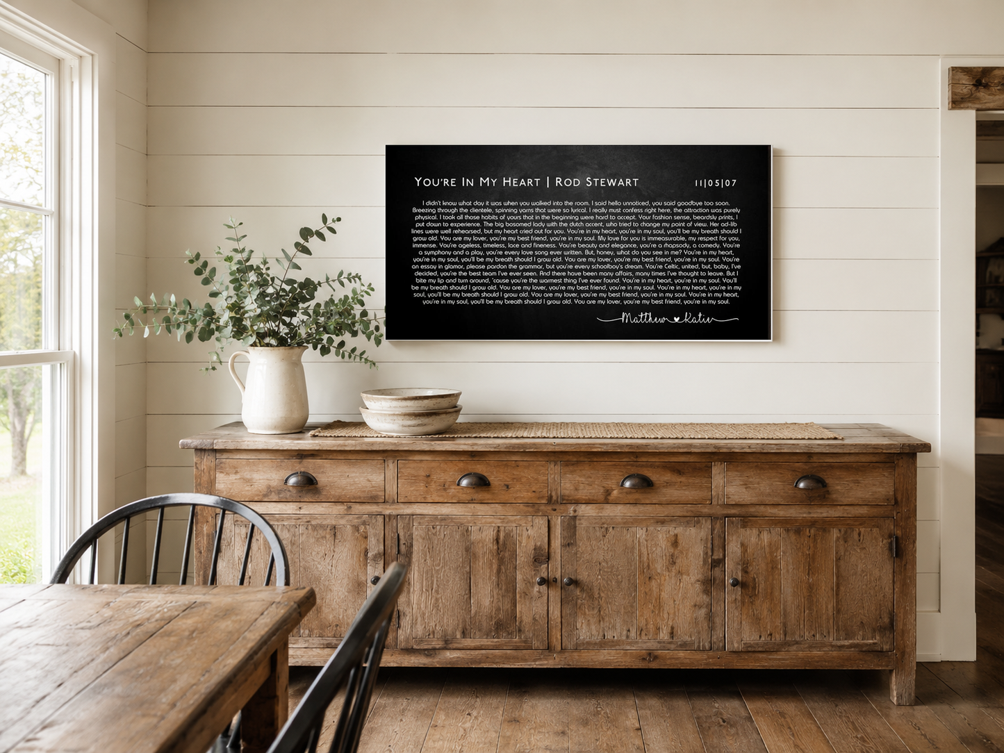Custom couple names and date song lyric canvas above a reclaimed oak sideboard in a farmhouse dining room