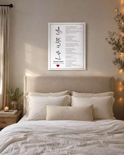 Custom song lyrics canvas print hanging above a linen bed in a warm neutral master bedroom