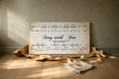Stay with You song lyrics canvas as a wedding gift, leaning on an oak floor with torn kraft paper, ribbon and gold wedding rings