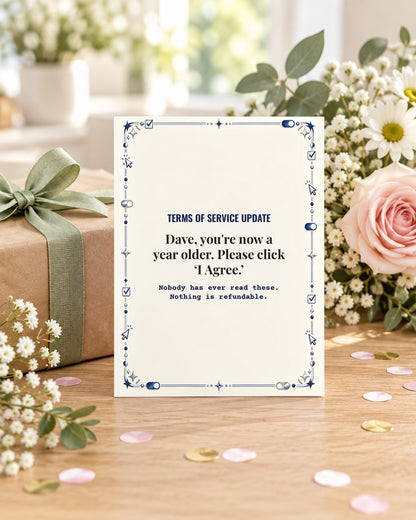 Funny birthday card displayed next to a wrapped gift and flowers