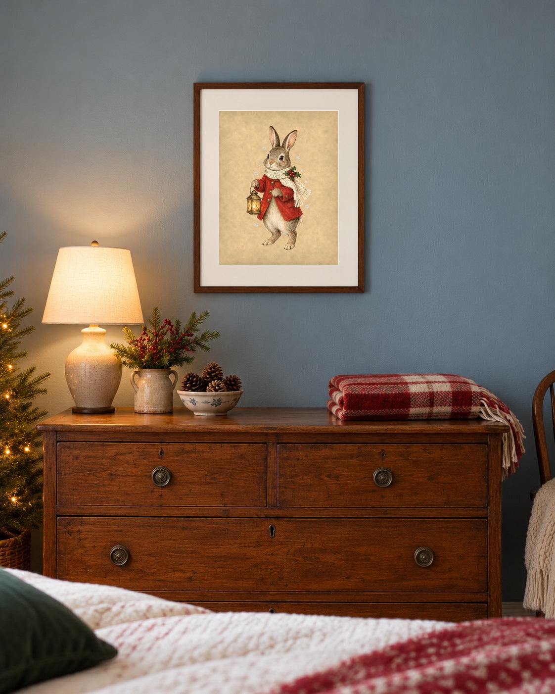 Framed vintage Christmas bunny print above a dresser in a dusty-blue bedroom