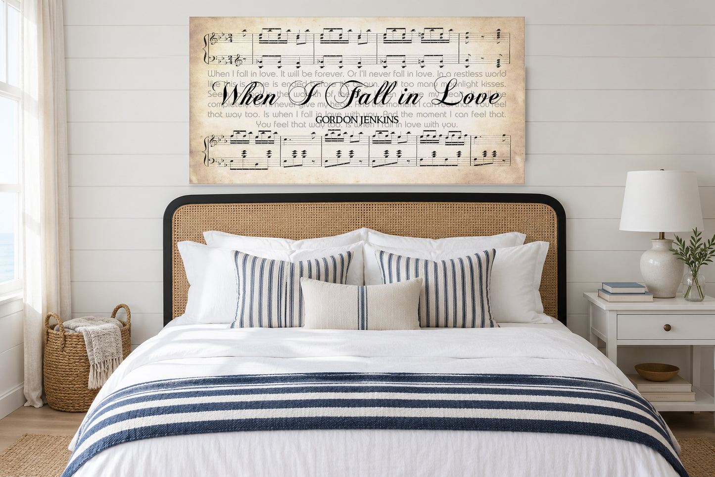When I Fall in Love sheet music canvas above a cane headboard in a bright coastal bedroom
