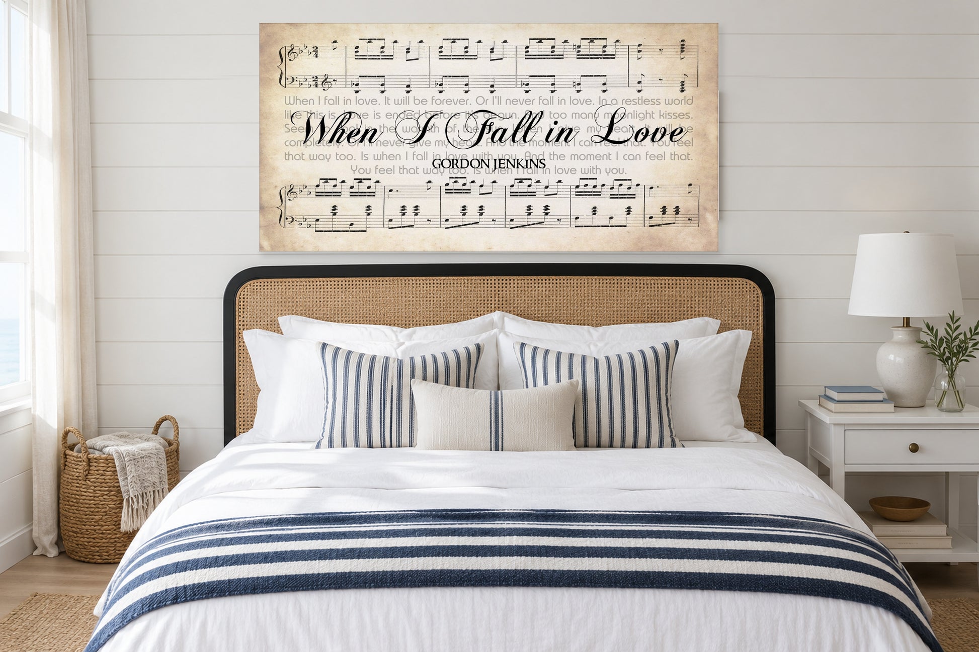When I Fall in Love sheet music canvas above a cane headboard in a bright coastal bedroom